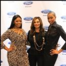 Tina Knowles poses for a picture backstage with two models wearing her designed apparel